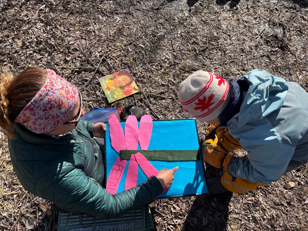 Jen working with a student to build a flower out of felt. The book